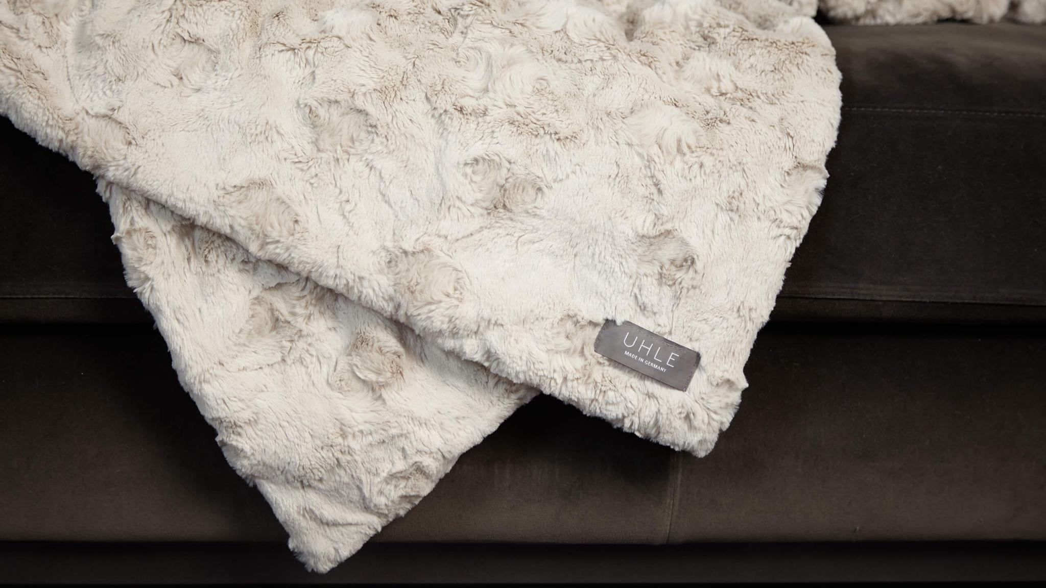 Nahaufnahme Davos Sandstein hellgrau herrlich weiche kuschlige elegante hochwertige Webfelldecke Webpelzdecke aus sogenanntem Teddy-Stoff auf Wohnzimmer Sofa Couch