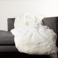 Hochflorige Webpelzdecke reinweiß sehr weich kuschlig warm auf dem Wohnzimmer Sofa mit Fütterung aus feinem weißem Wollstoff
